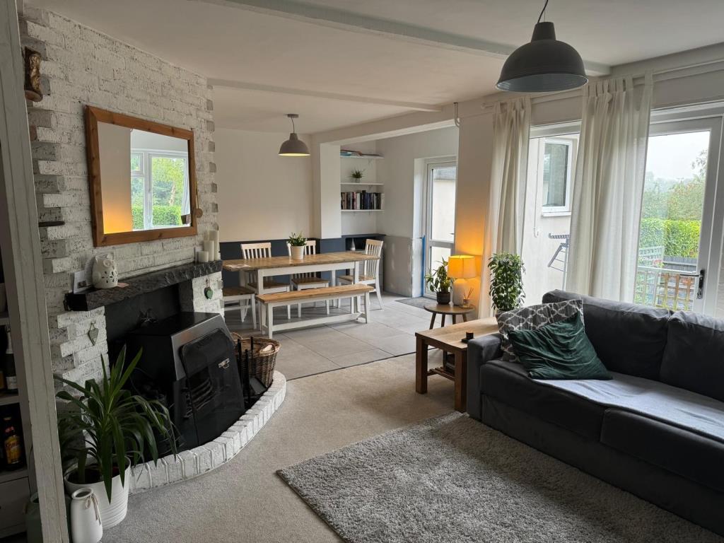 Lot: 55 - THREE-BEDROOM END-TERRACE HOUSE - Living and dining room with tiled floor and open fireplace